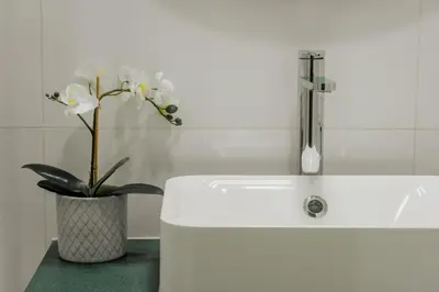 a white sink with a vase with white flowers in it at Comfort Zone beach apartment in Quarteira