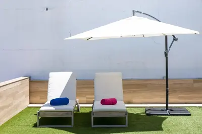 two chairs sitting on grass under an umbrella at Casa Amarela Guesthouse in Albufeira