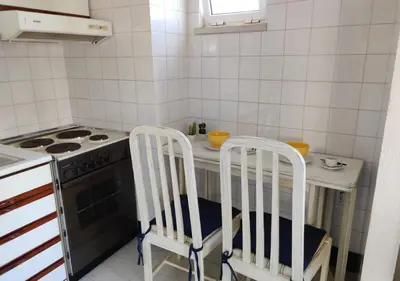 a kitchen with a stove and two chairs in it at Cosy studio apartment in Vilamoura in Quarteira