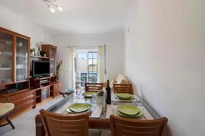 a dining room with a table and chairs and a television at T2 Bosque de São José in Albufeira