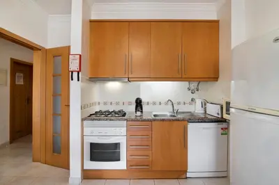 a kitchen with white appliances and wooden cabinets at T2 Bosque de São José in Albufeira