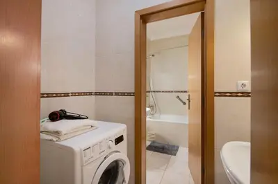 a bathroom with a washing machine and a tub at T2 Bosque de São José in Albufeira