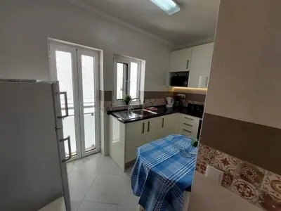 a kitchen with white cabinets and a blue plaid table at Encosta do Sol Apartamentos in Albufeira