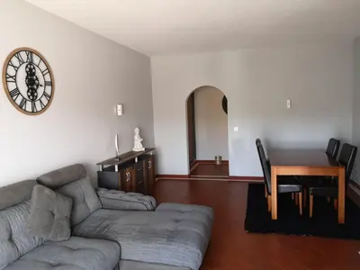 a living room with a couch and a table and a clock at Apartamento Recanto do Avô in Albufeira