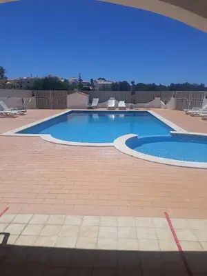 a large swimming pool in a yard with a patio at studio para 2 pessoas in Albufeira