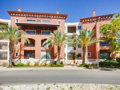 a building with palm trees in front of it at AL - Victoria Gardens in Vilamoura