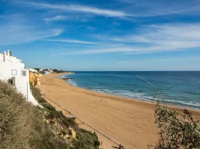 a beach with a white building and the ocean at Old Town Apartment by Stay ici Algarve Holiday Rental in Albufeira
