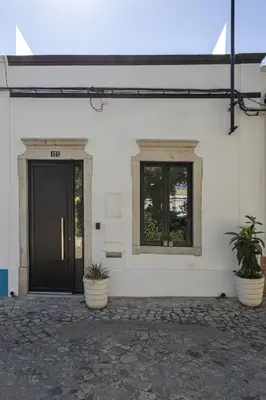 a building with a black door and two potted plants at Casa da Praca - City Center - Faro in Faro