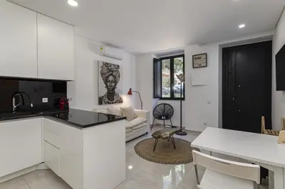a kitchen with white cabinets and a living room at Casa da Praca - City Center - Faro in Faro