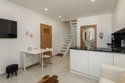 a kitchen and living room with a desk and a staircase at Casa da Praca - City Center - Faro in Faro