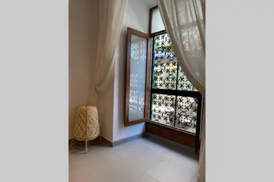 a room with a window with a curtain and a chair at Janelas Verdes 37 in Faro