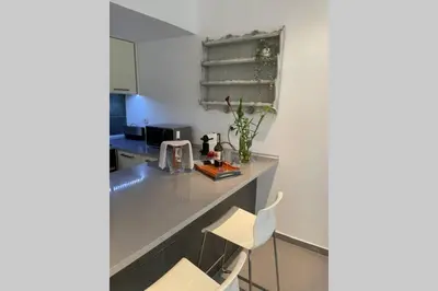 a kitchen with a counter and two white chairs at Janelas Verdes 37 in Faro