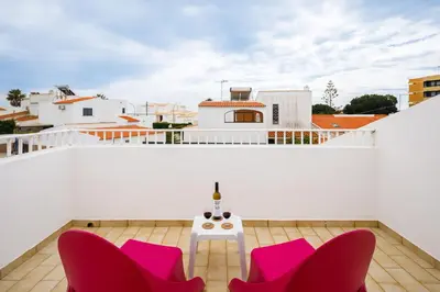 a balcony with pink chairs and a table at Villa Nobre by The Portuguese Butler in Albufeira
