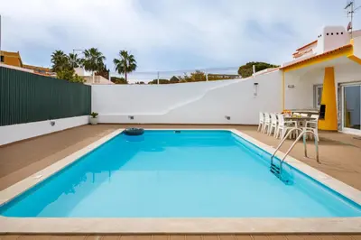 a swimming pool with a table and chairs next to a building at Villa Nobre by The Portuguese Butler in Albufeira