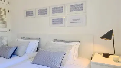 a white bed with blue and white pillows and a lamp at Vila Chez Lee, 219 Aldeia do Golf-CleverDetails - Sleeps 6, quiet area in Vilamoura