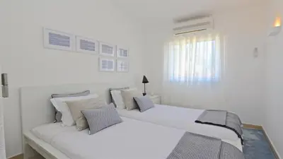 a white bedroom with two beds and a window at Vila Chez Lee, 219 Aldeia do Golf-CleverDetails - Sleeps 6, quiet area in Vilamoura