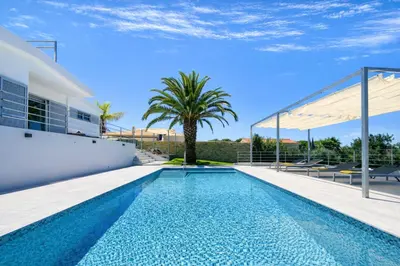 a swimming pool in the backyard of a house with a palm tree at Moderna by Check-in Portugal in Quarteira