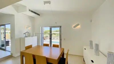 a dining room with a wooden table and a window at Moderna by Check-in Portugal in Quarteira