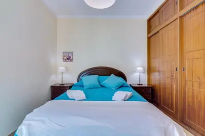 a bedroom with a large bed with blue pillows at InfiniteSeaView - Quarteira at Homesbyfc in Quarteira