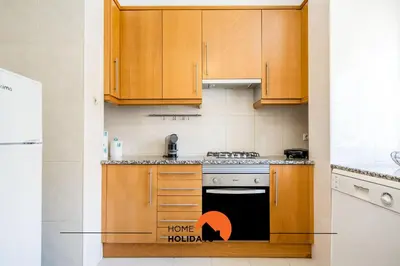a kitchen with wooden cabinets and a stove top oven at #055 São José V by Home Holidays in Albufeira