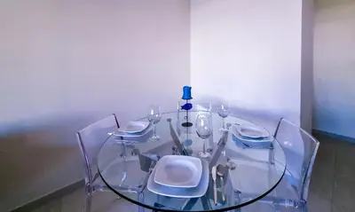 a glass table with chairs and a bottle on top of it at FLH Vilamoura Summer Flat with Pool in Vilamoura