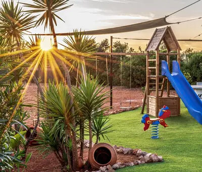 a playground with a slide and palm trees and the sunset at Casa Lusitania 19 in Faro