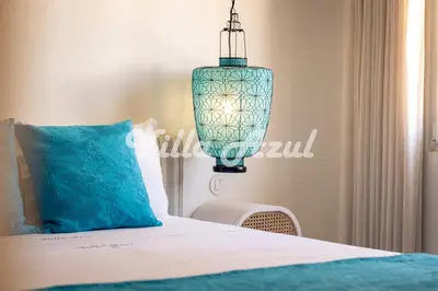 a bedroom with a bed with a blue pillow and a chandelier at Elegant villa with private pool in Quarteira in Vilamoura