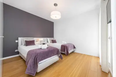 two beds in a room with white walls and wood floors at ELLE Design Villa by OCvillas - Private Heated Pool and Jacuzzi in Albufeira