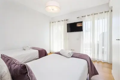 two beds in a room with a tv and windows at ELLE Design Villa by OCvillas - Private Heated Pool and Jacuzzi in Albufeira