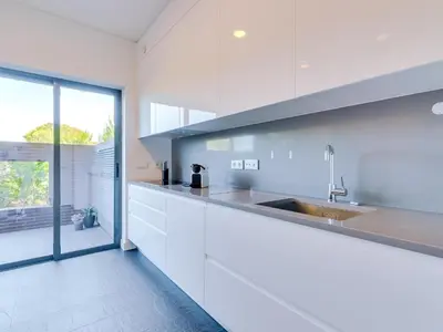 a kitchen with white cabinets and a large window at L'orangerie modern 1bdr apartment, ground floor in Vilamoura