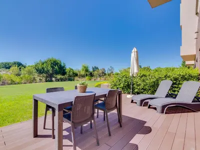 a patio with a table and chairs and an umbrella at L'orangerie modern 1bdr apartment, ground floor in Vilamoura