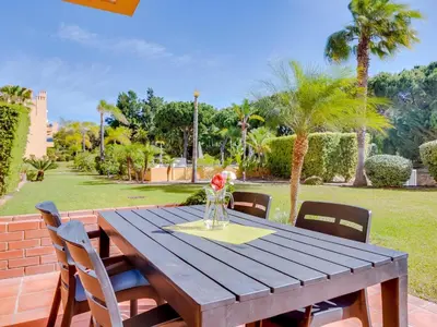 a wooden table with chairs and a vase of flowers on it at AL - Apartamento Vila Sol F5 L in Vilamoura