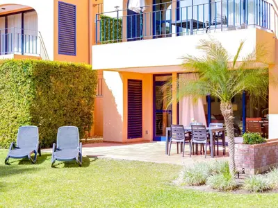 a patio with chairs and a table and a palm tree at AL - Apartamento Vila Sol F5 L in Vilamoura