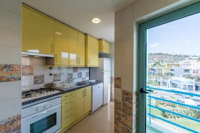 a kitchen with yellow cabinets and a large window at Admirable 1 bedroom Marina view apt. Albufeira in Albufeira