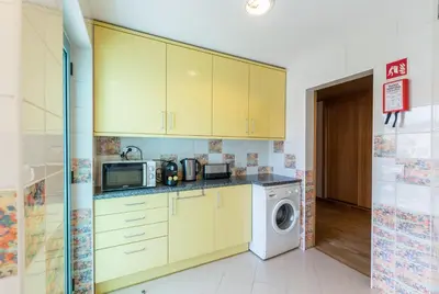 a kitchen with yellow cabinets and a washer and dryer at Admirable 1 bedroom Marina view apt. Albufeira in Albufeira