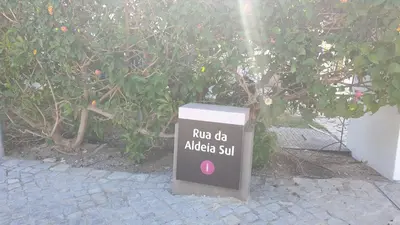 a trash can sitting on a sidewalk next to a bush at Seagull Rooftop Beach @150 m in Vale do Lobo