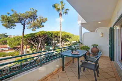 a balcony with a table and chairs and palm trees at Casa Valerie in Vale do Lobo