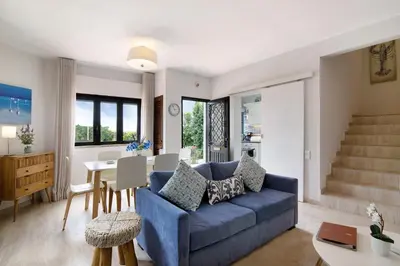 a living room with a blue couch and a table at Casa Harlequin in Vale do Lobo