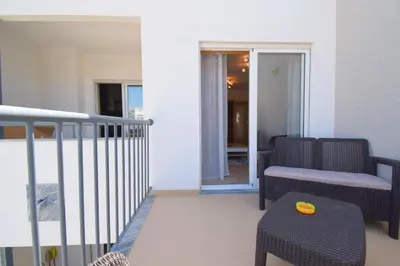 a balcony with a couch and a chair and a table at Perfect New Apartment in Albufeira in Albufeira