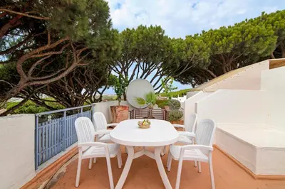 a white table and chairs on a balcony with trees at Villa Apple in Vale do Lobo