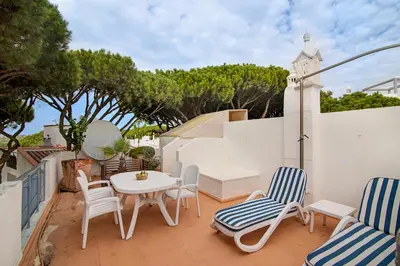 a patio with chairs and a table and a clock at Villa Apple in Vale do Lobo