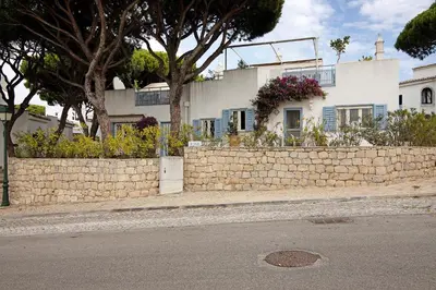 a brick retaining wall next to a house with flowers at Villa Apfel in Vale do Lobo