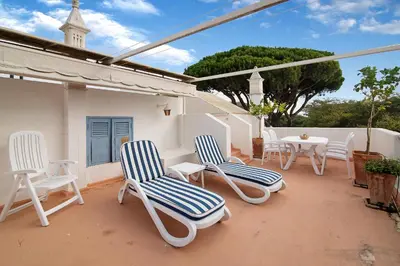 a patio with white chairs and a table and a church at Villa Apfel in Vale do Lobo