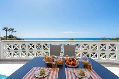 a blue table with food on a balcony with the ocean at Aveiros by the Sea by Intiholidays in Albufeira