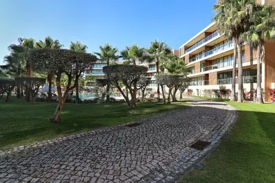 a cobblestone path in front of a building with palm trees at Salgados 4seasons Apartment in Albufeira