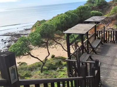 a wooden walkway leading to a beach with benches at Villa Sunshine in Albufeira