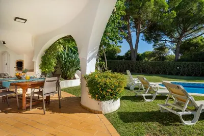 a patio with a table and chairs and a pool at Casa de Gales - Vilamoura in Vilamoura