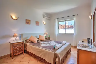 a bedroom with a large bed and a window at Villa Papi by Villa Plus in Albufeira