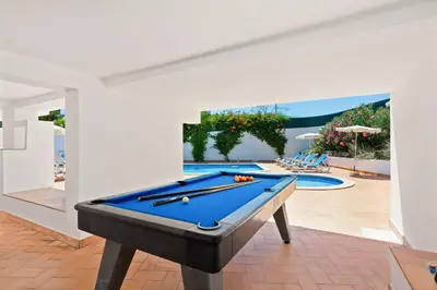 a pool table in a room with a swimming pool at Villa Papi by Villa Plus in Albufeira
