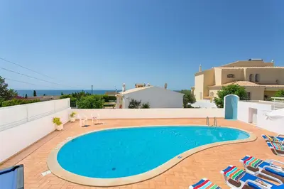 a swimming pool on the side of a house with lawn chairs and a swimming pool at Villa Primavera by Villa Plus in Albufeira